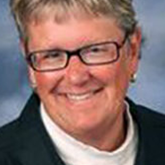 Woman with glasses smiling, wearing a white shirt and a black blazer.