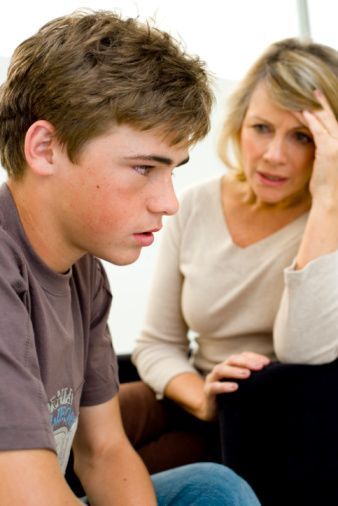 Teen boy with concerned expression and woman with hand on forehead.