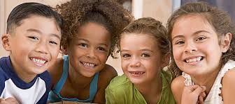 Four diverse children smiling and looking at the viewer.