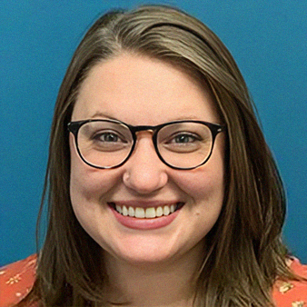 Woman with glasses smiling at the camera, wearing an orange floral shirt, with a blue background.