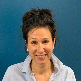 Woman with dark hair in a bun smiles; blue shirt and background.