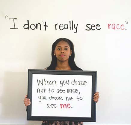 A young Black woman holds a sign that says, 