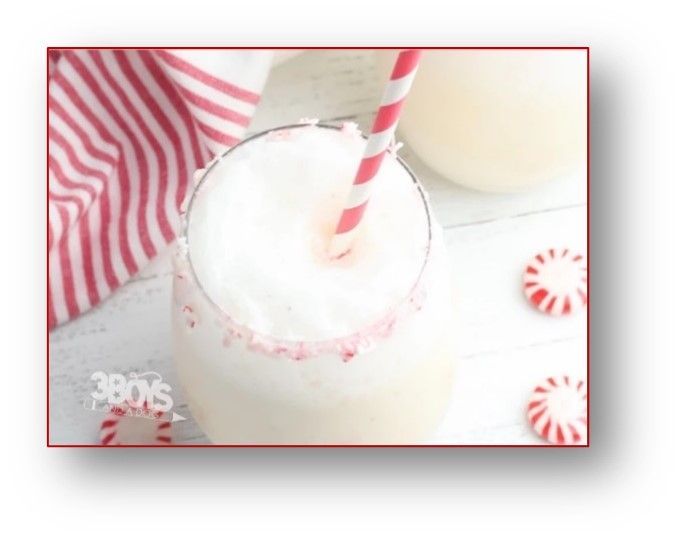 Peppermint milkshake in a glass with a striped straw, surrounded by candy canes and a red and white striped cloth.