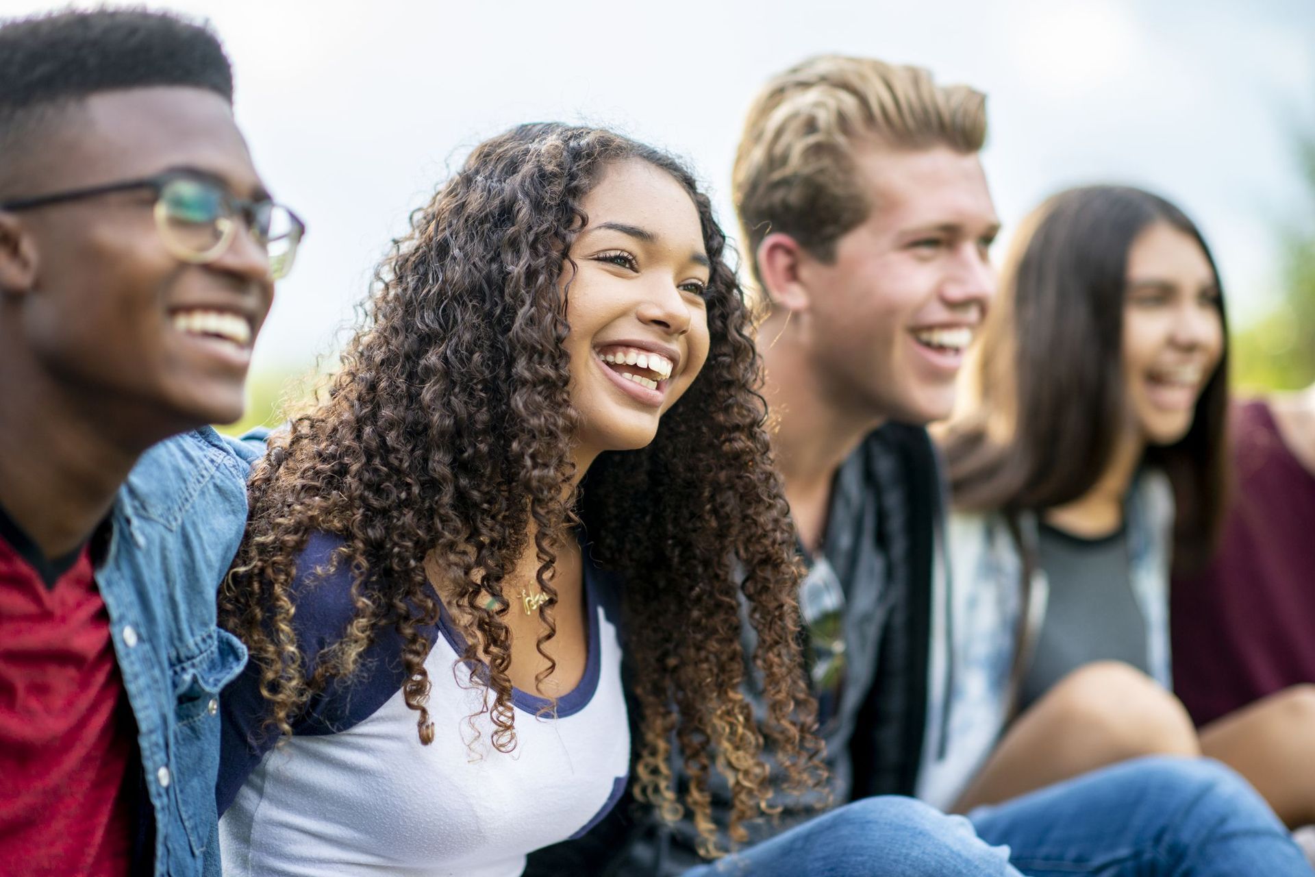 Group of diverse teens laughing together outdoors.