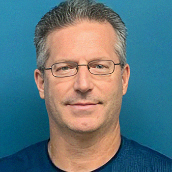 Man with glasses, graying hair, smiling against a blue background.