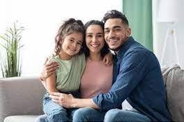 Family of three smiling, embracing on a couch. Woman, man, and child.