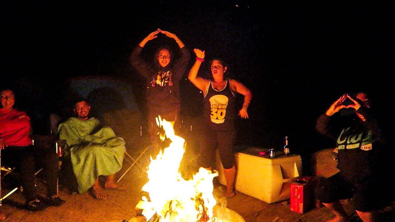 People around a campfire, two making an