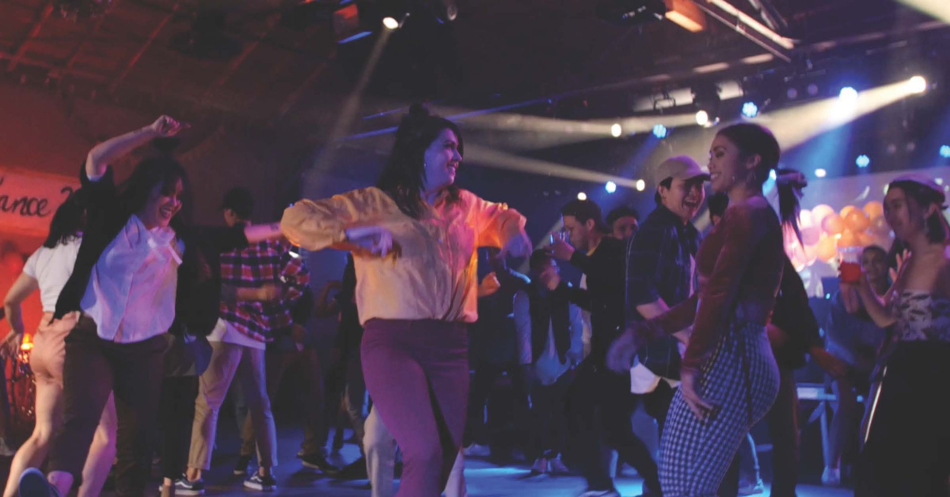 People dancing at a concert, lit by colorful stage lights.