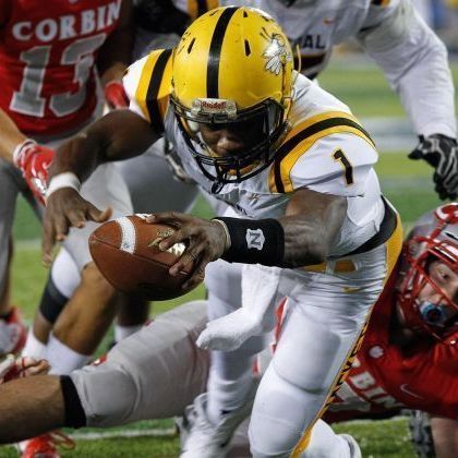 Football player in yellow helmet, running with ball, white and gold uniform, tackling.