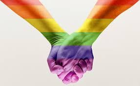 Two hands clasped, painted with the colors of the rainbow flag, symbolizing LGBTQ+ solidarity.