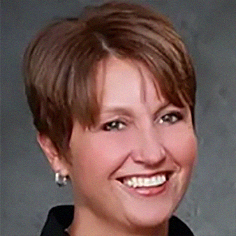 Woman with short, brown hair smiling, dark background.