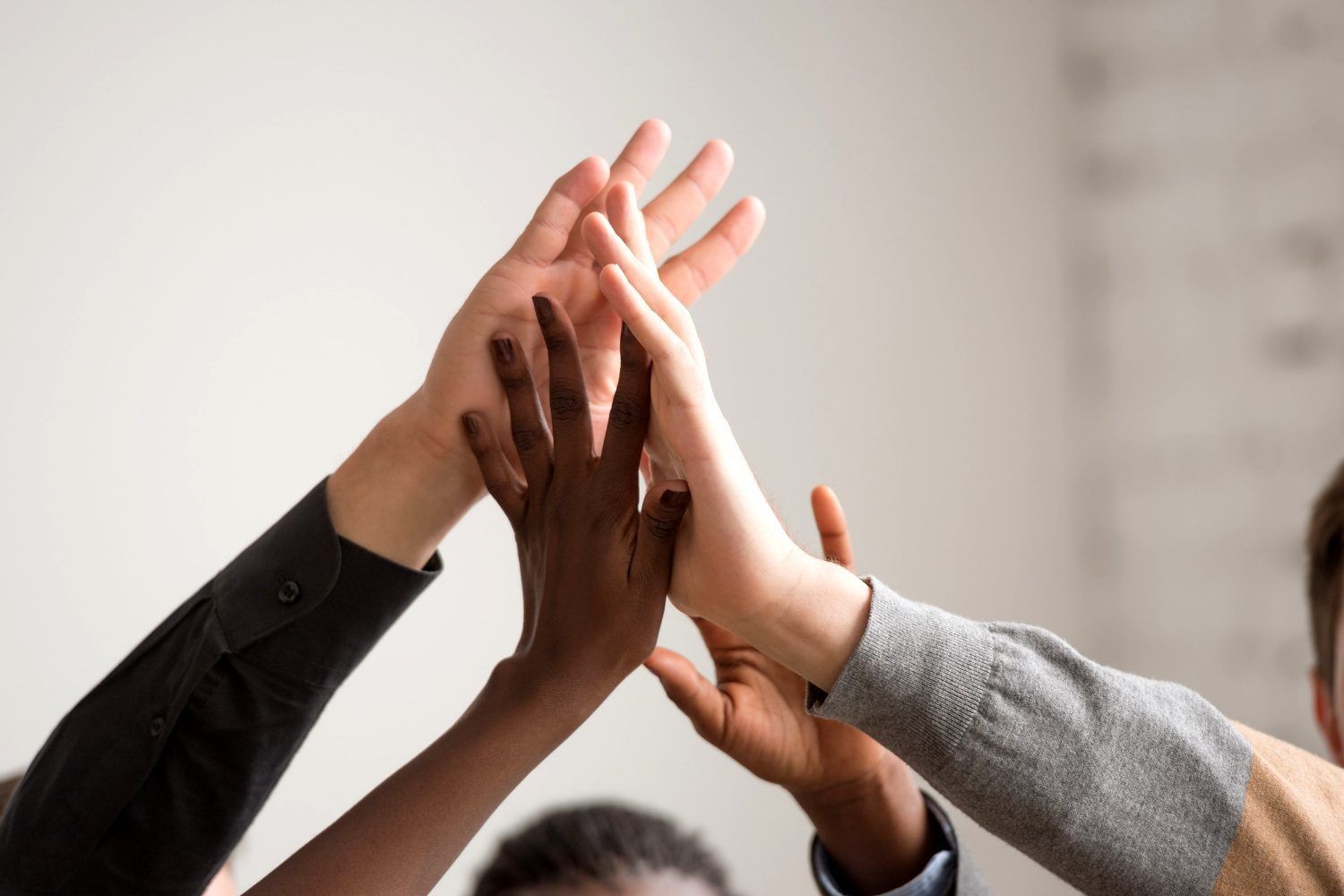 Hands of diverse people in a high-five gesture.
