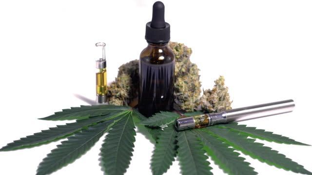 Cannabis products: flower buds, oil bottles, vape pen cartridges, and marijuana leaf on white background.