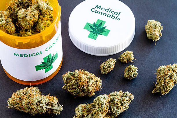 Medical cannabis buds and a prescription bottle with a cannabis leaf symbol.
