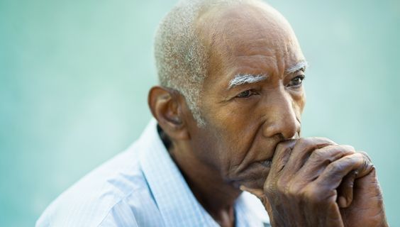 Elderly Black man with gray hair and concerned expression, biting his nails.