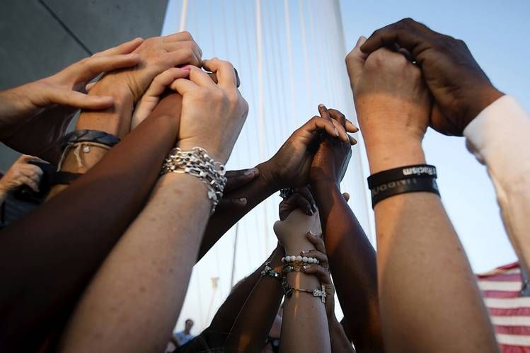 Diverse hands clasped together, reaching upwards, symbolizing unity and support.