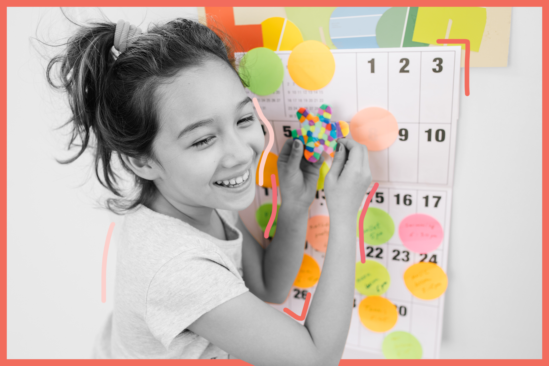Smiling girl with ponytail decorates a calendar with colorful sticky notes and craft items.