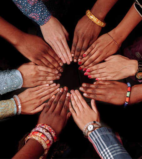 Hands of various skin tones joined in a circle, wearing bracelets and jewelry.