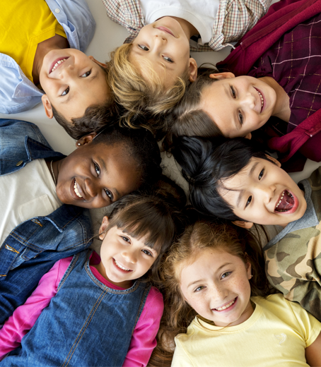 Group of diverse children smiling, heads together in a circle.