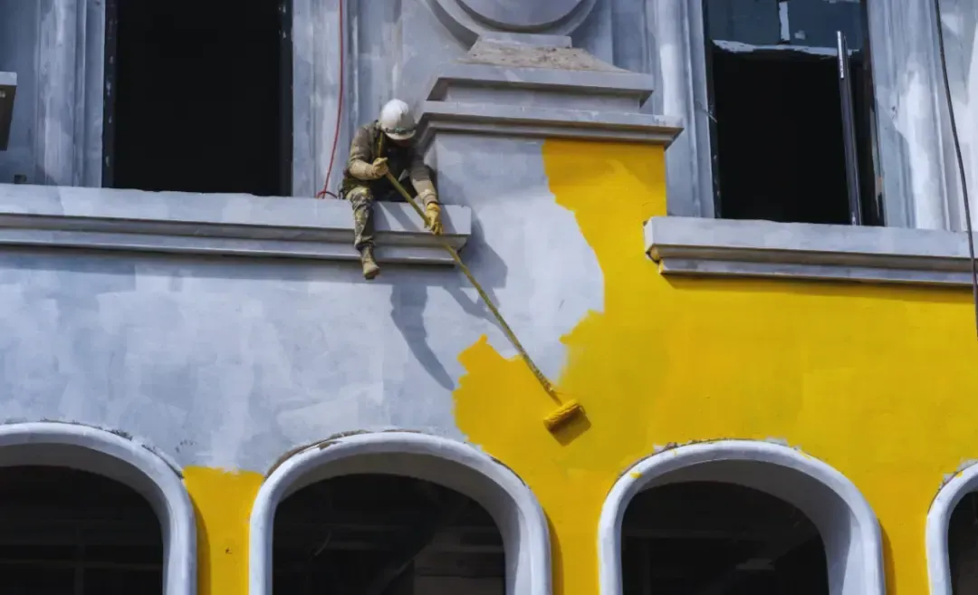 man doing exterior paint on a building