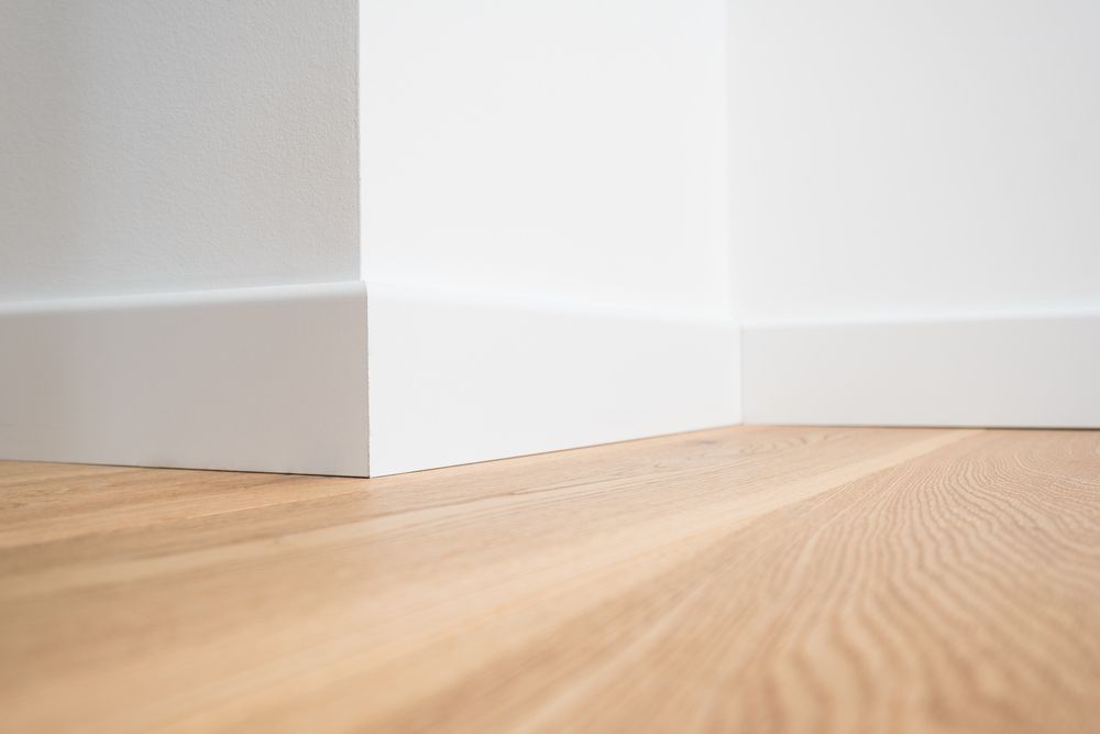 Empty room corner with white walls and light wood floor