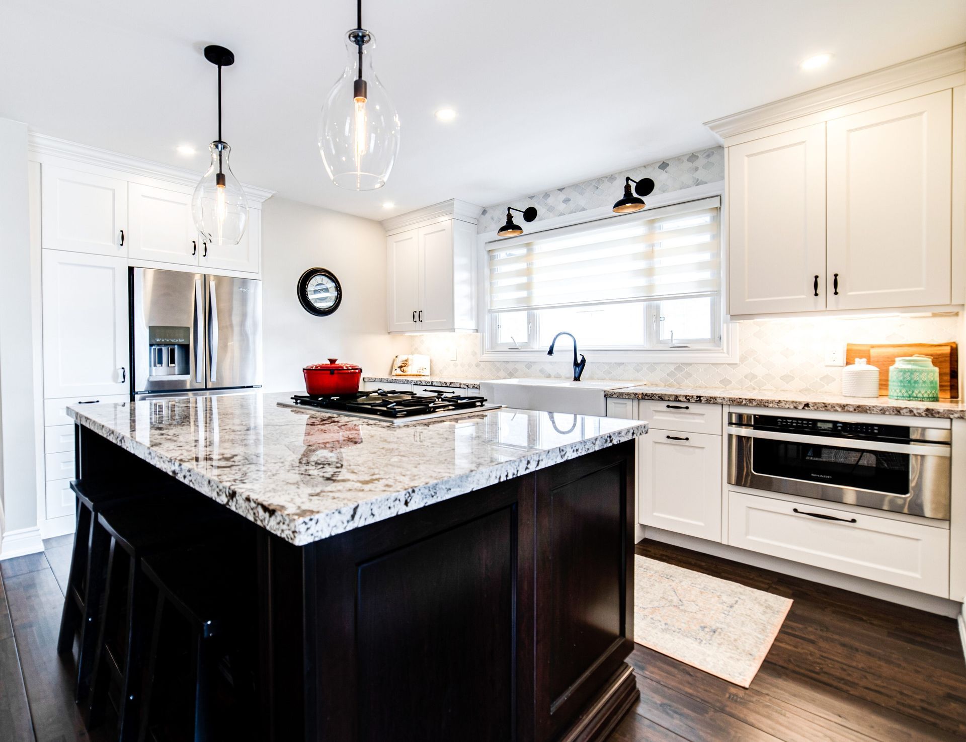 A kitchen with white cabinets , granite counter tops , stainless steel appliances and a large island.