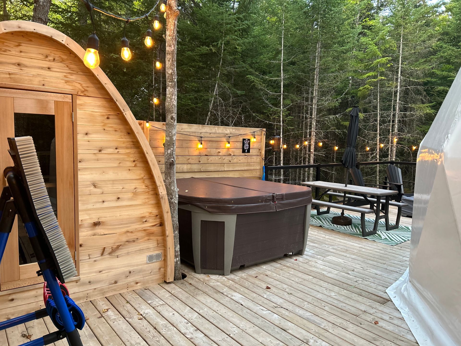 A hot tub is sitting on a wooden deck next to a tent.