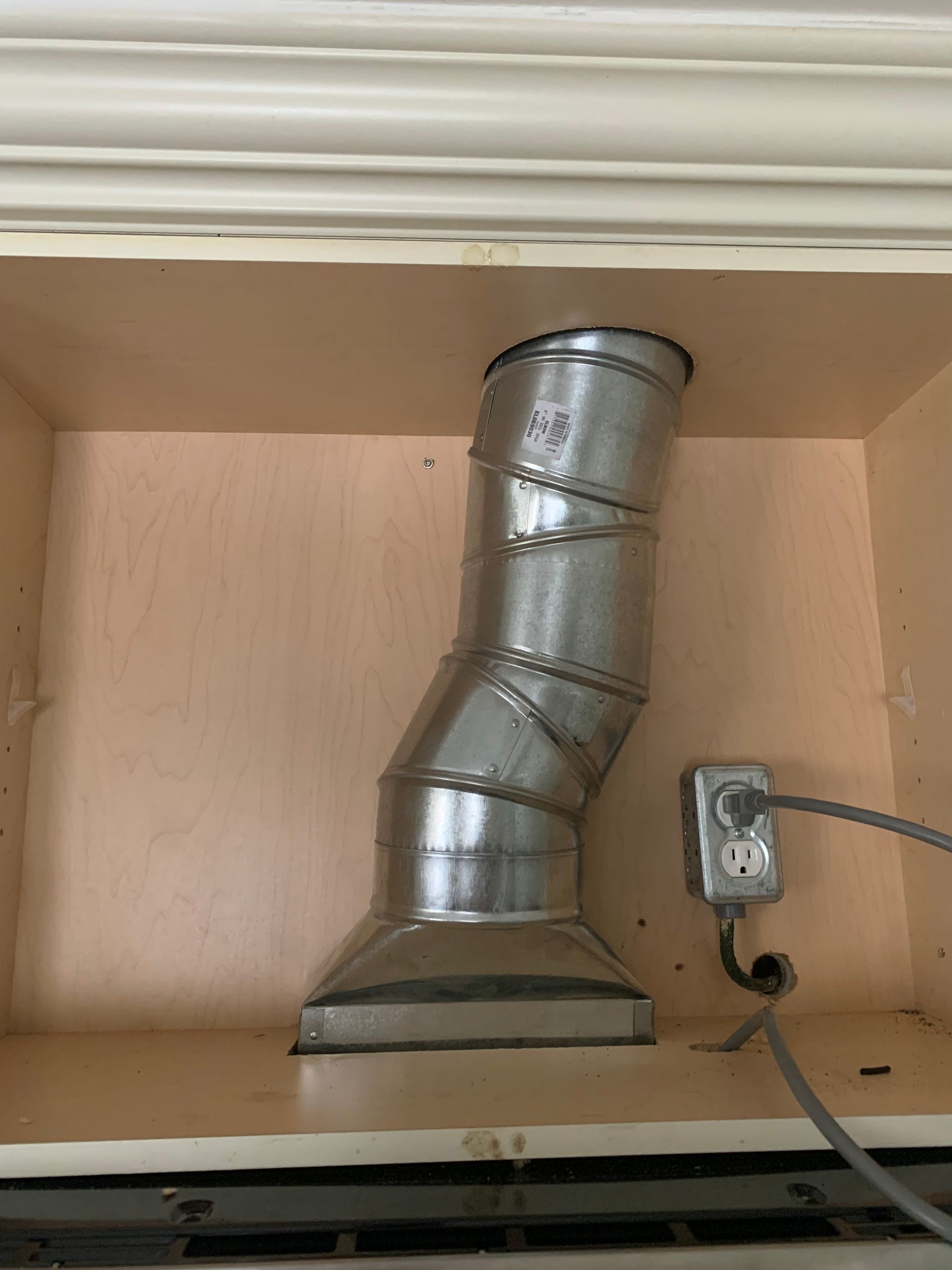 A metal pipe is hanging from the ceiling of a cabinet.
