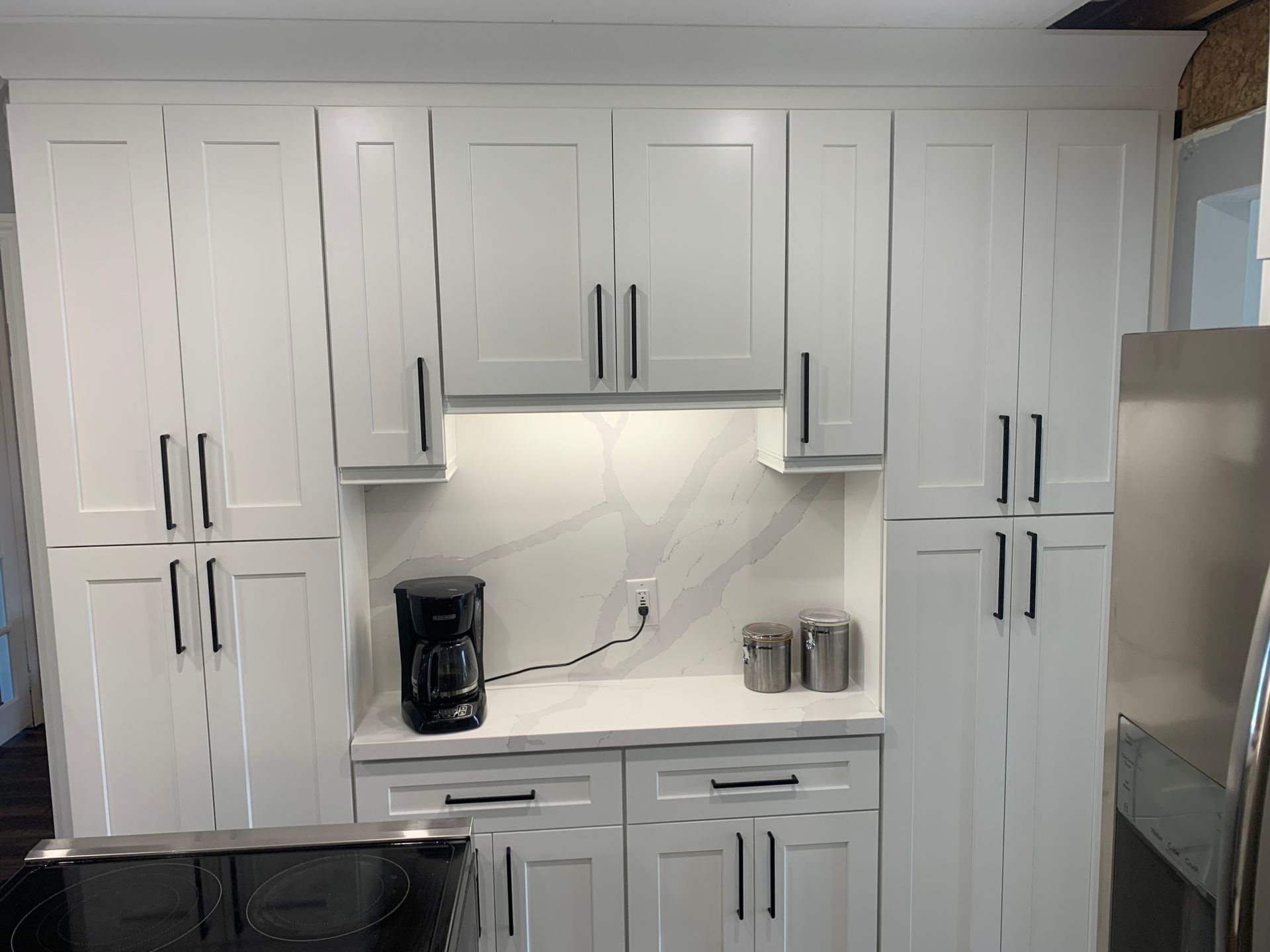 A kitchen with white cabinets and a coffee maker on the counter.