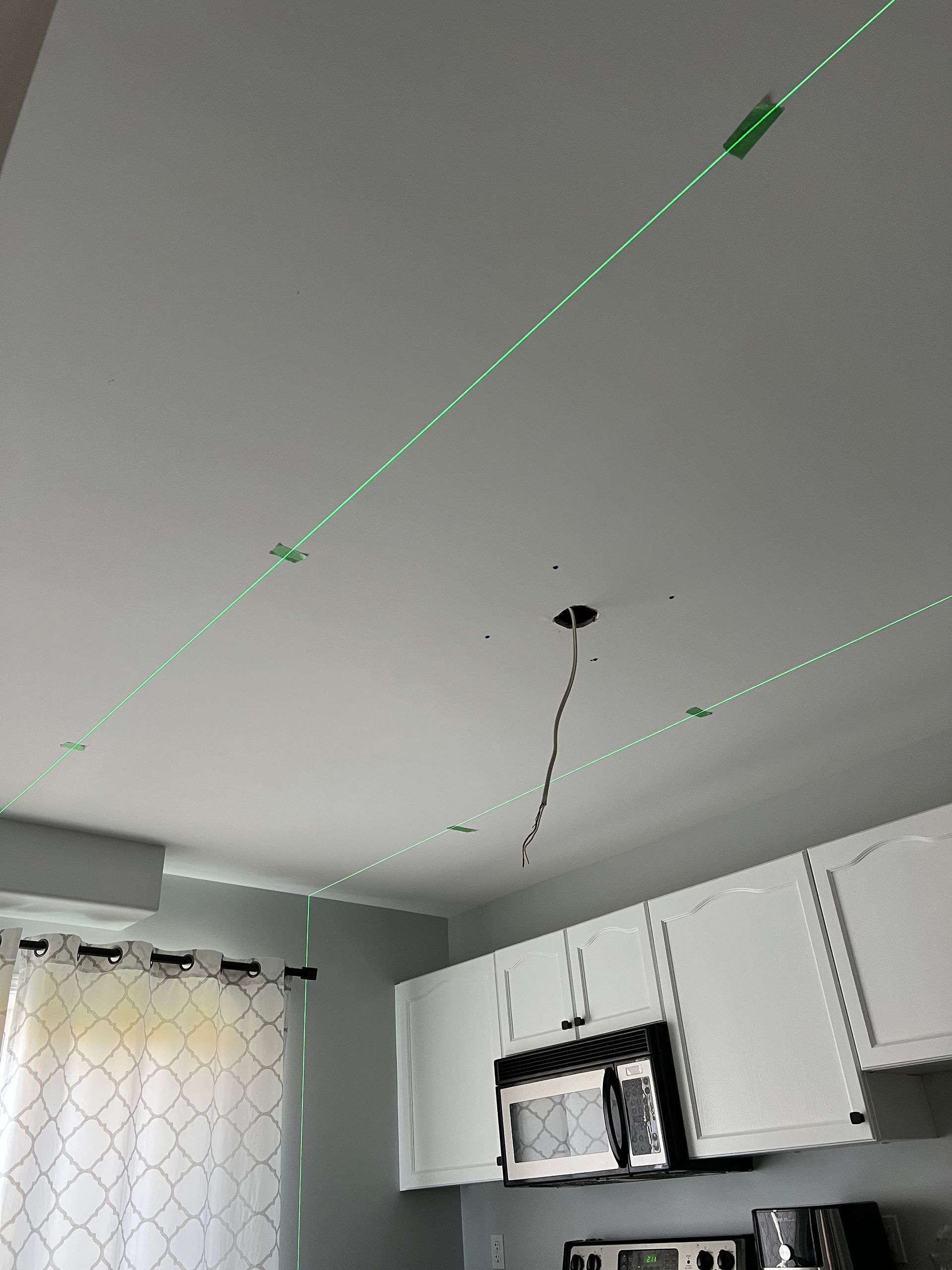 A kitchen with white cabinets and a green tape on the ceiling.