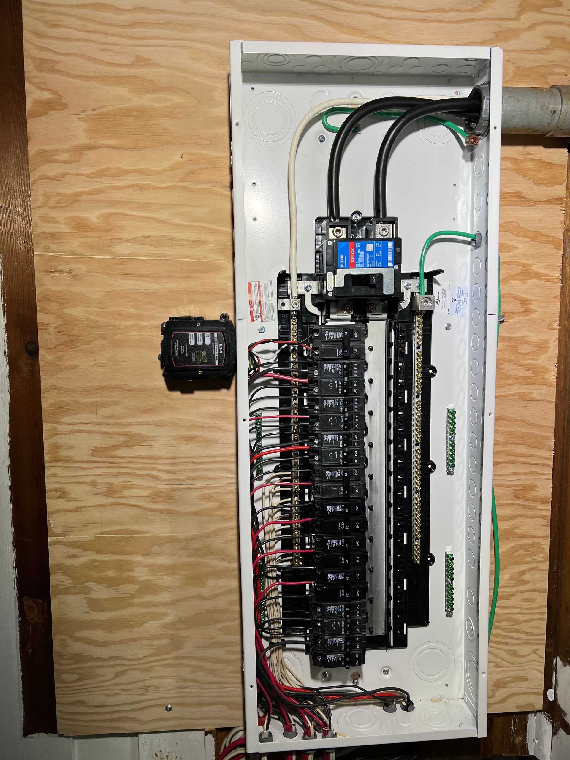 A white electrical box is sitting on a wooden wall.