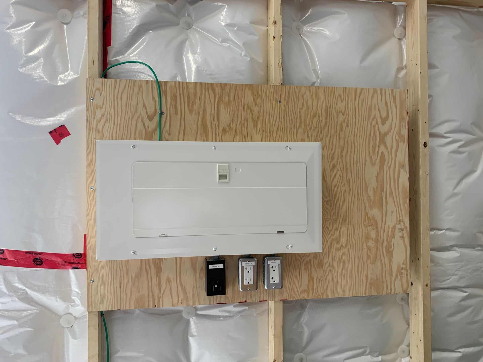A white electrical box is mounted to a wooden wall
