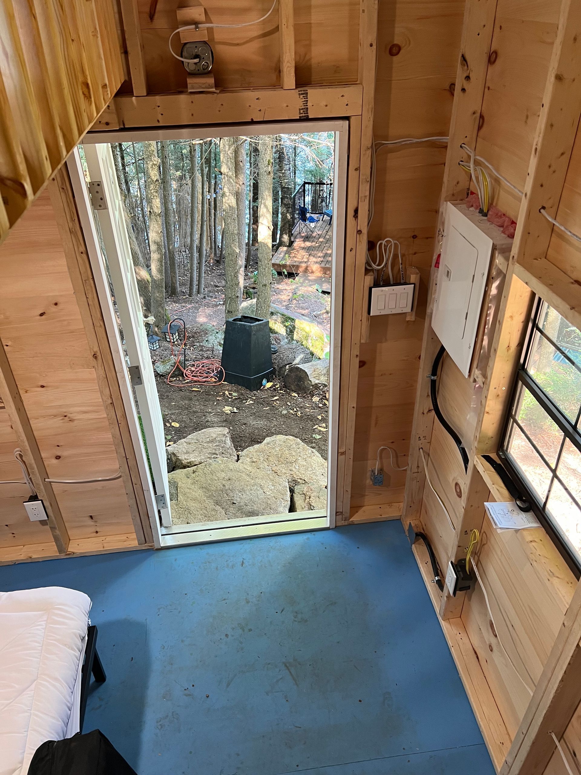 An aerial view of a wooden cabin with a door open to a forest.