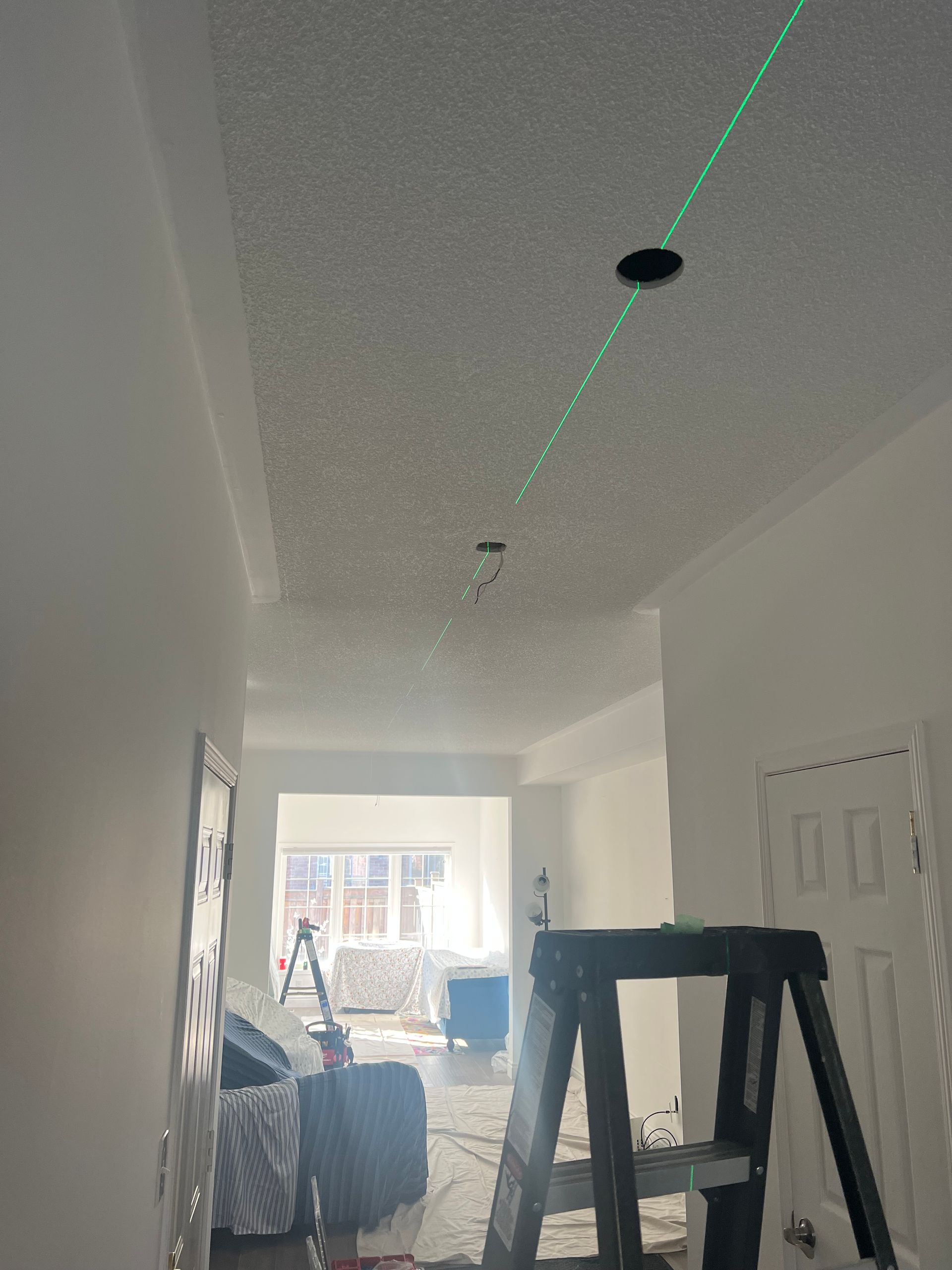 A person is using a laser to measure the ceiling of a room.