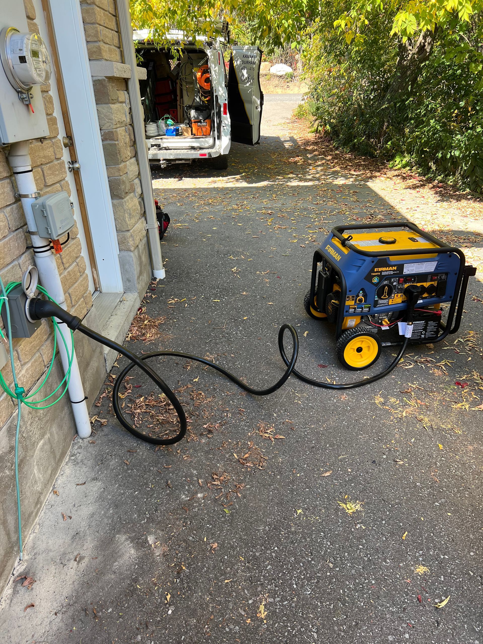 A generator is plugged into a wall next to a van.