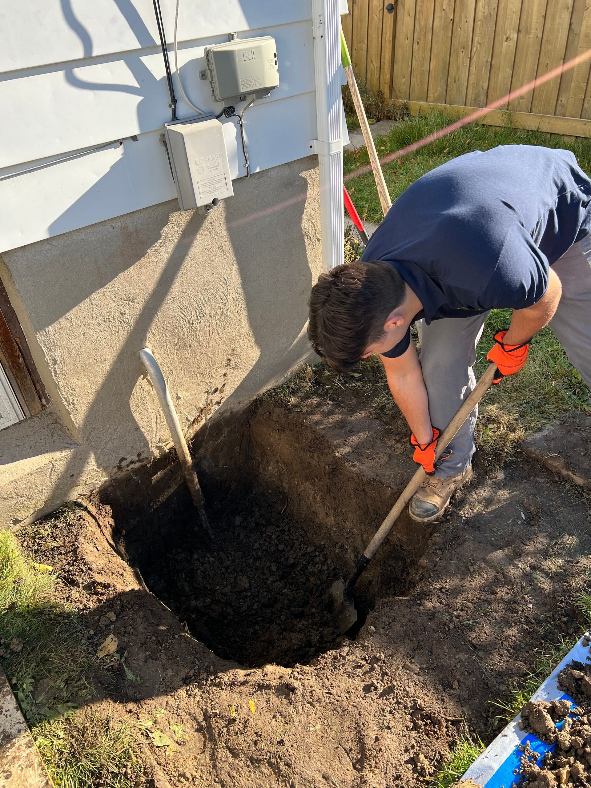 A man is digging a hole in the ground with a shovel.