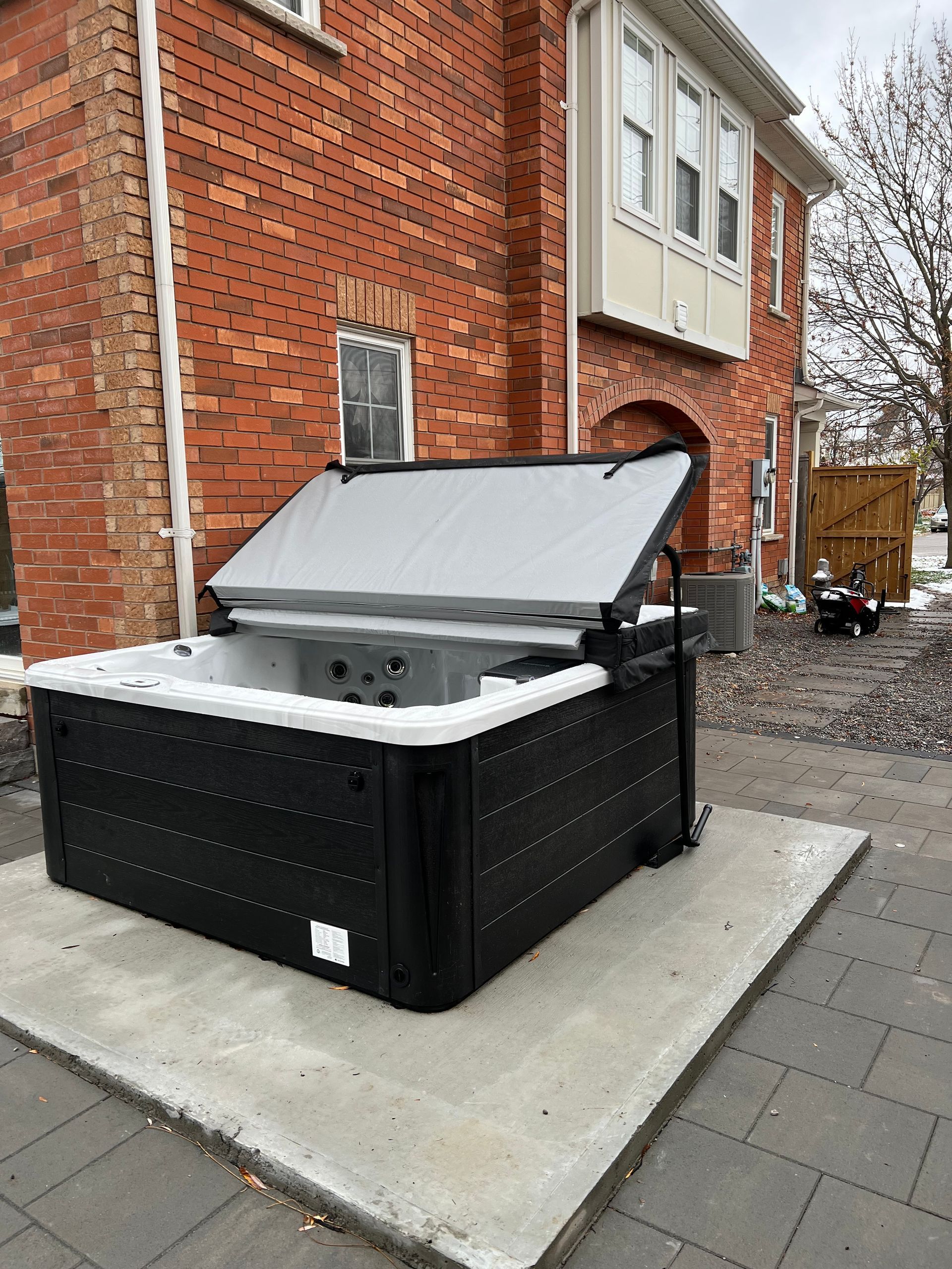 A black and white hot tub is sitting in front of a brick building.