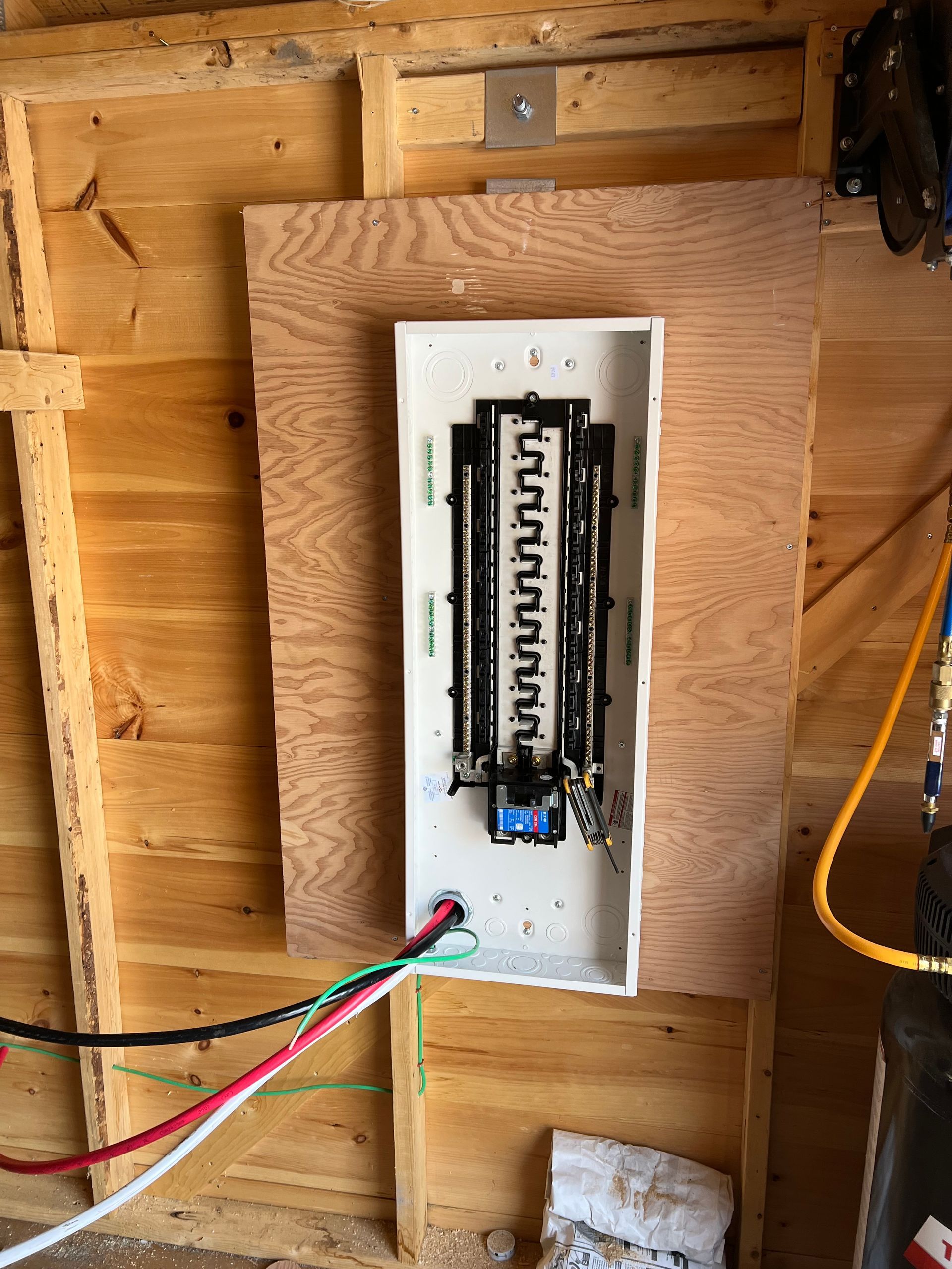 A electrical box is mounted on a wooden wall.