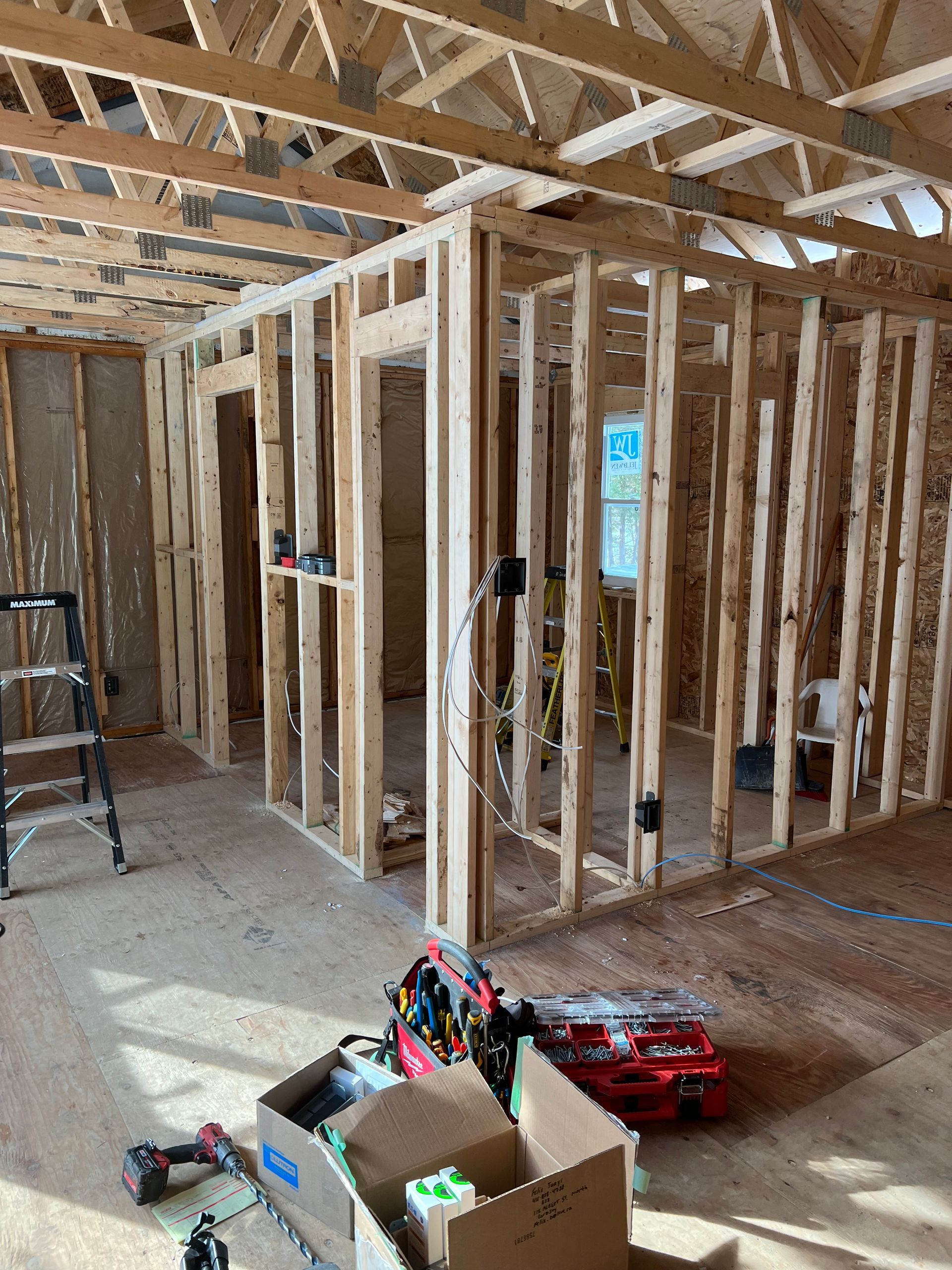 A room under construction with a ladder and boxes on the floor.