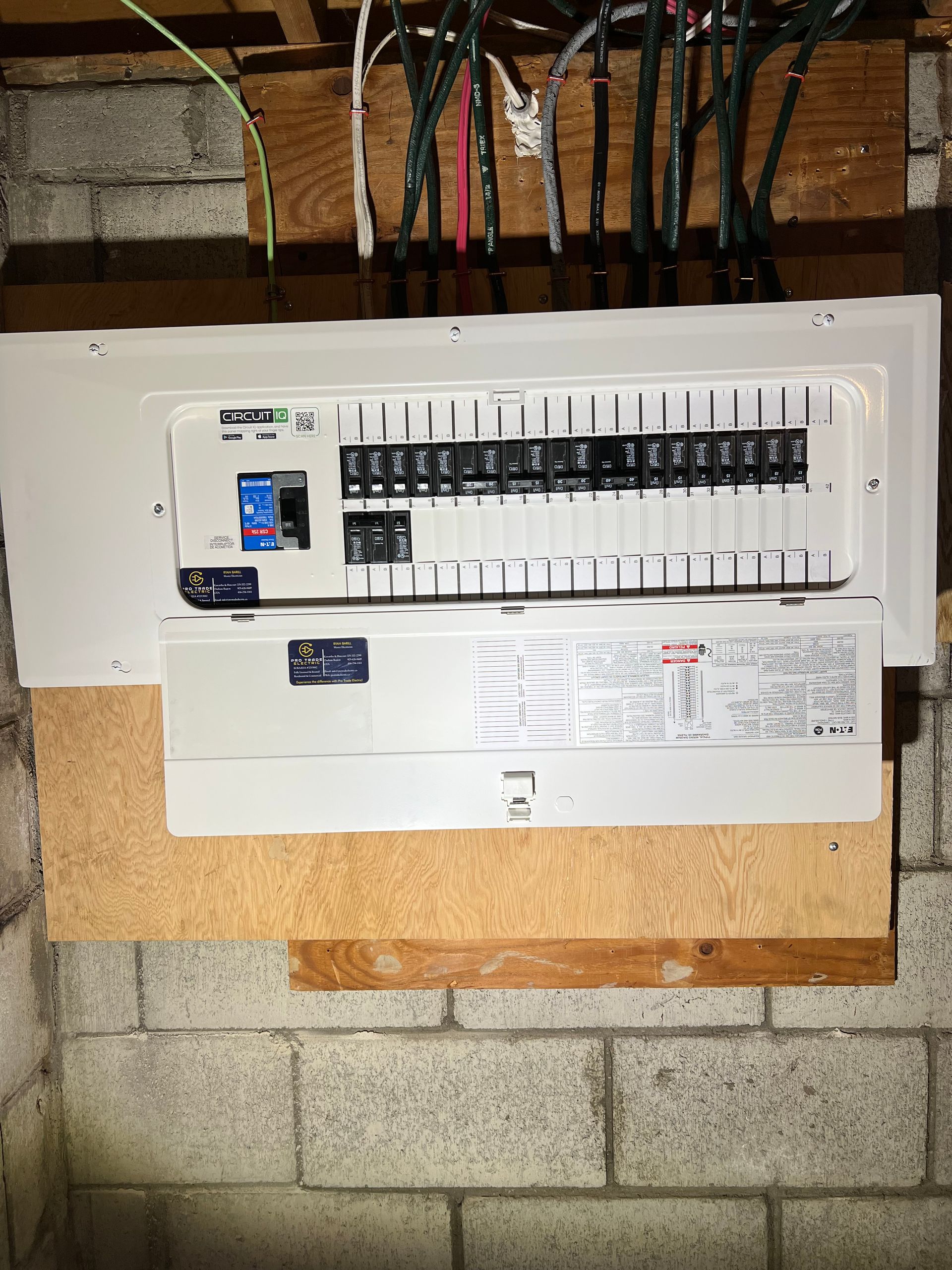 A white electrical box is hanging on a brick wall.