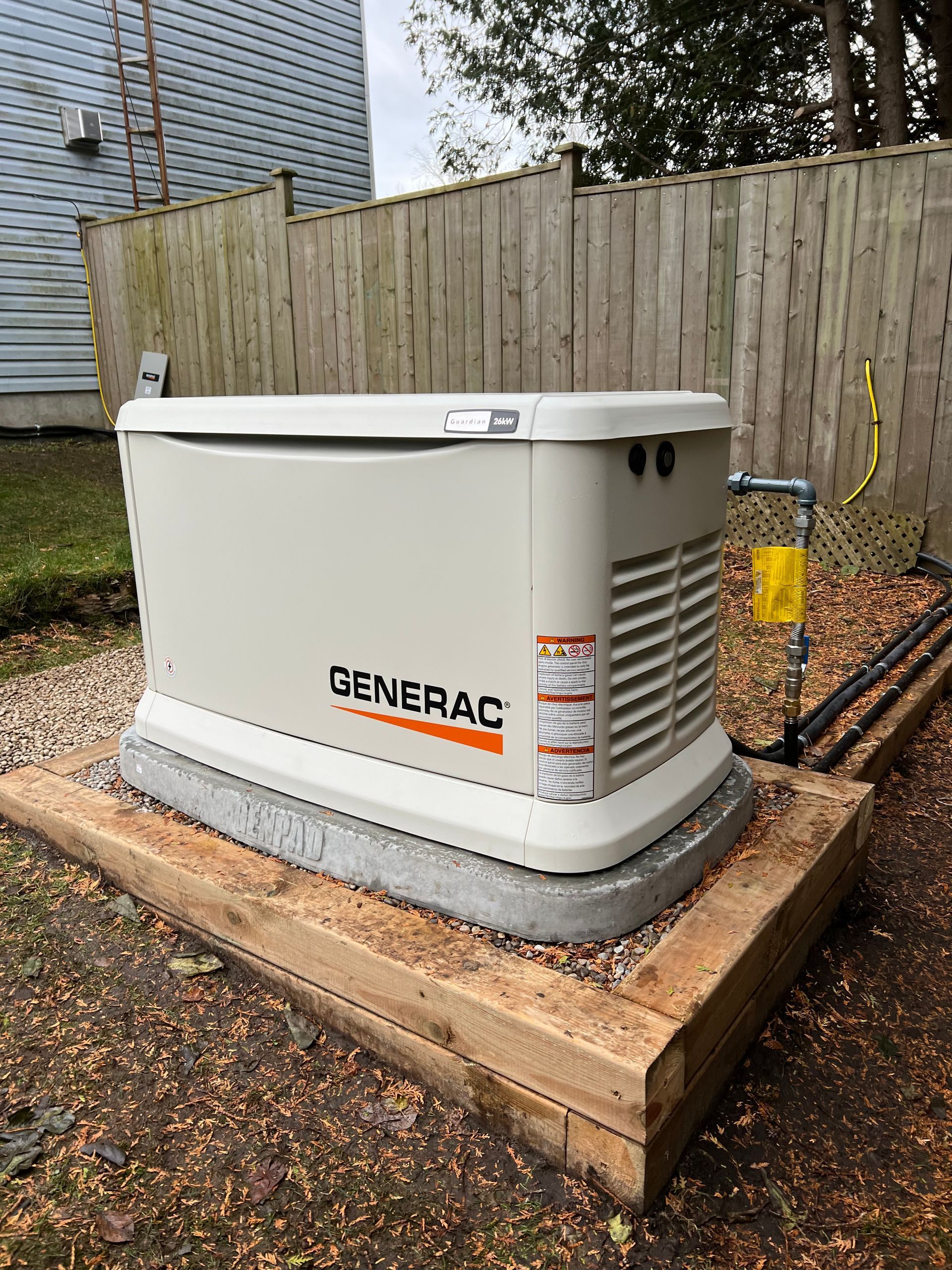 A generator is sitting on top of a wooden platform in a backyard.