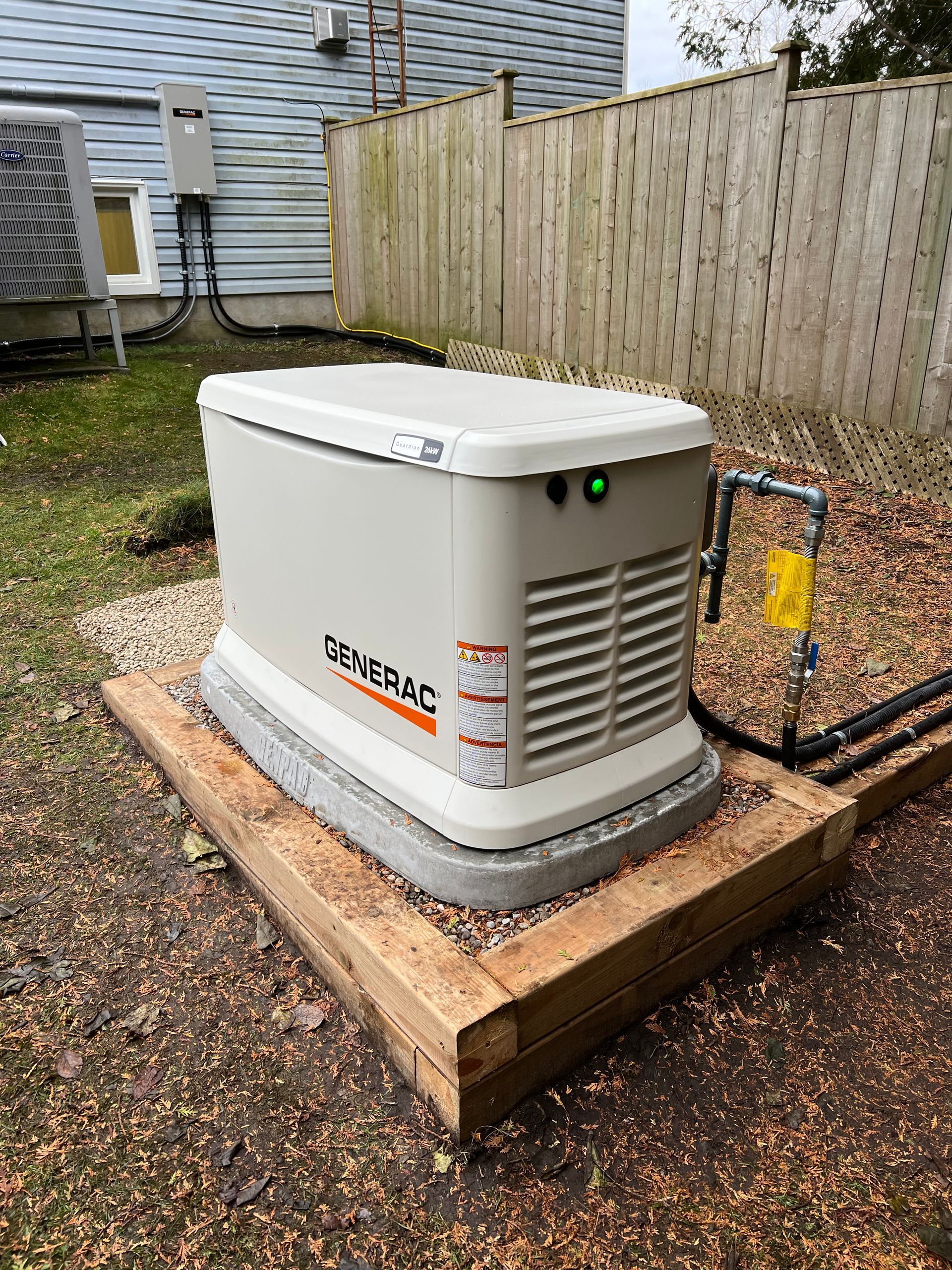 A generator is sitting on top of a wooden platform in the backyard of a house.