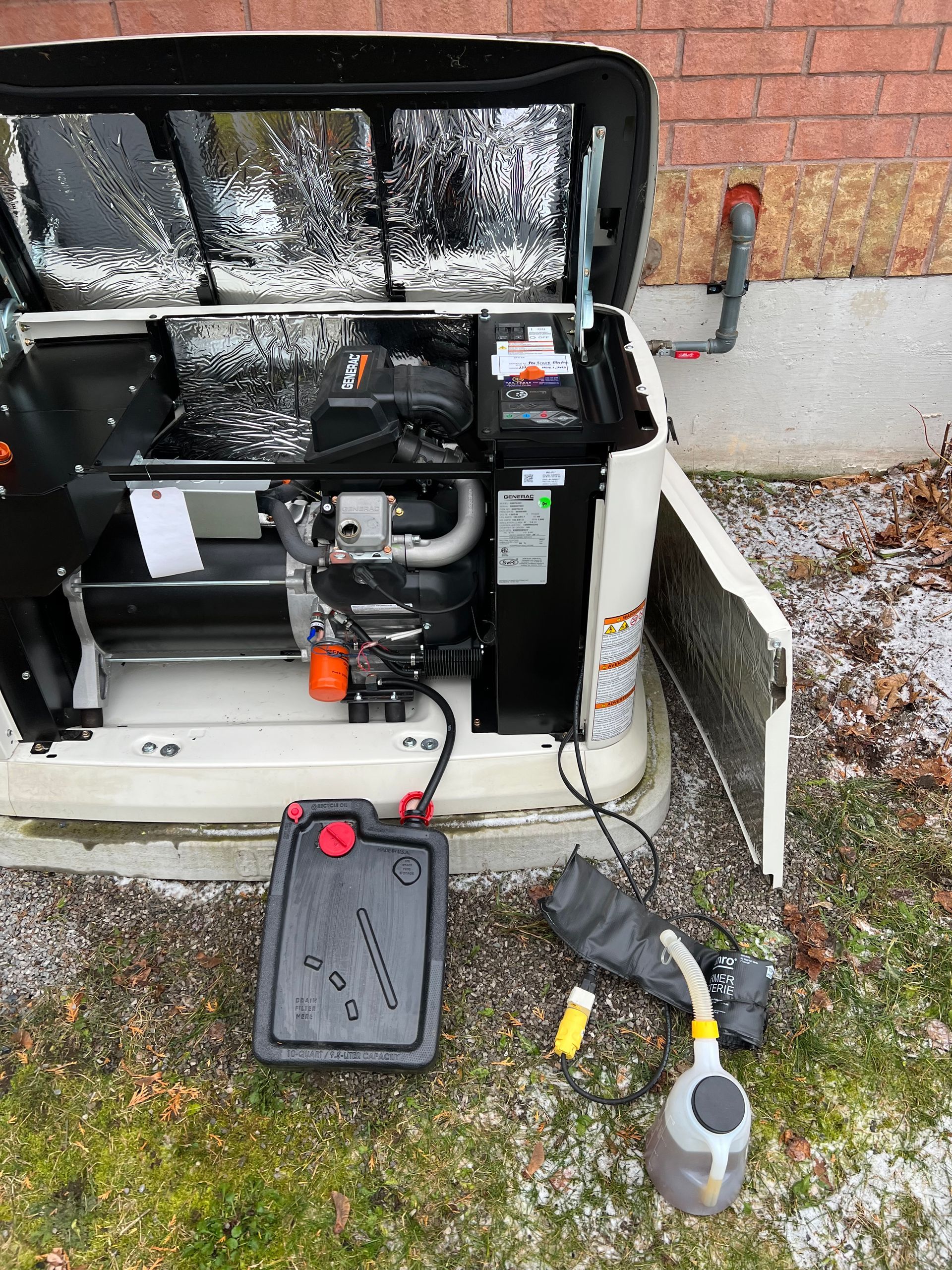 A generator is sitting on the ground next to a brick wall.