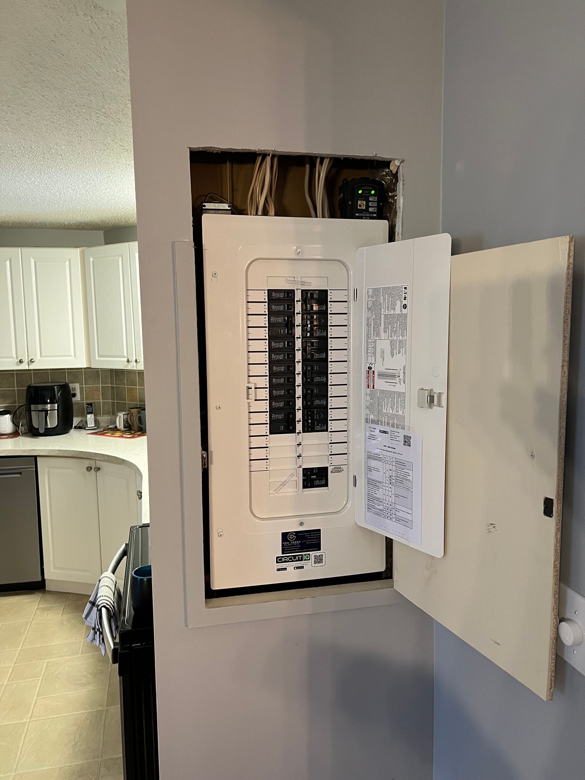 A electrical box is hanging on a wall in a kitchen.
