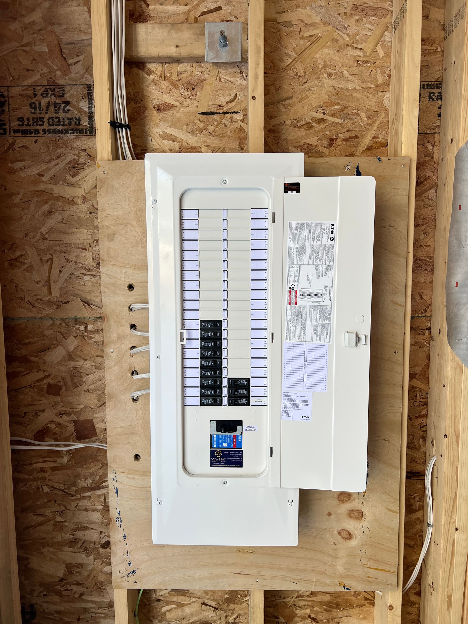 A white electrical box is mounted on a wooden wall.