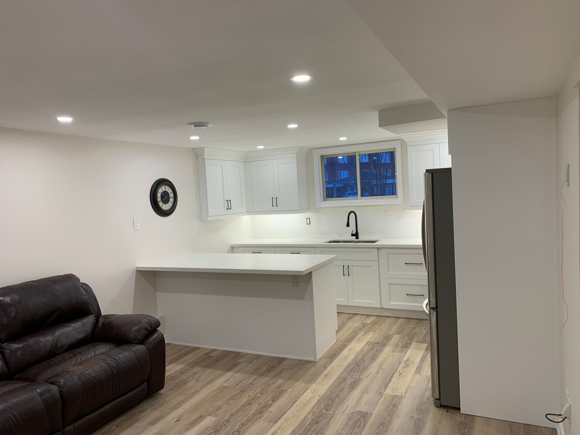 A living room with a couch and a kitchen in the background.
