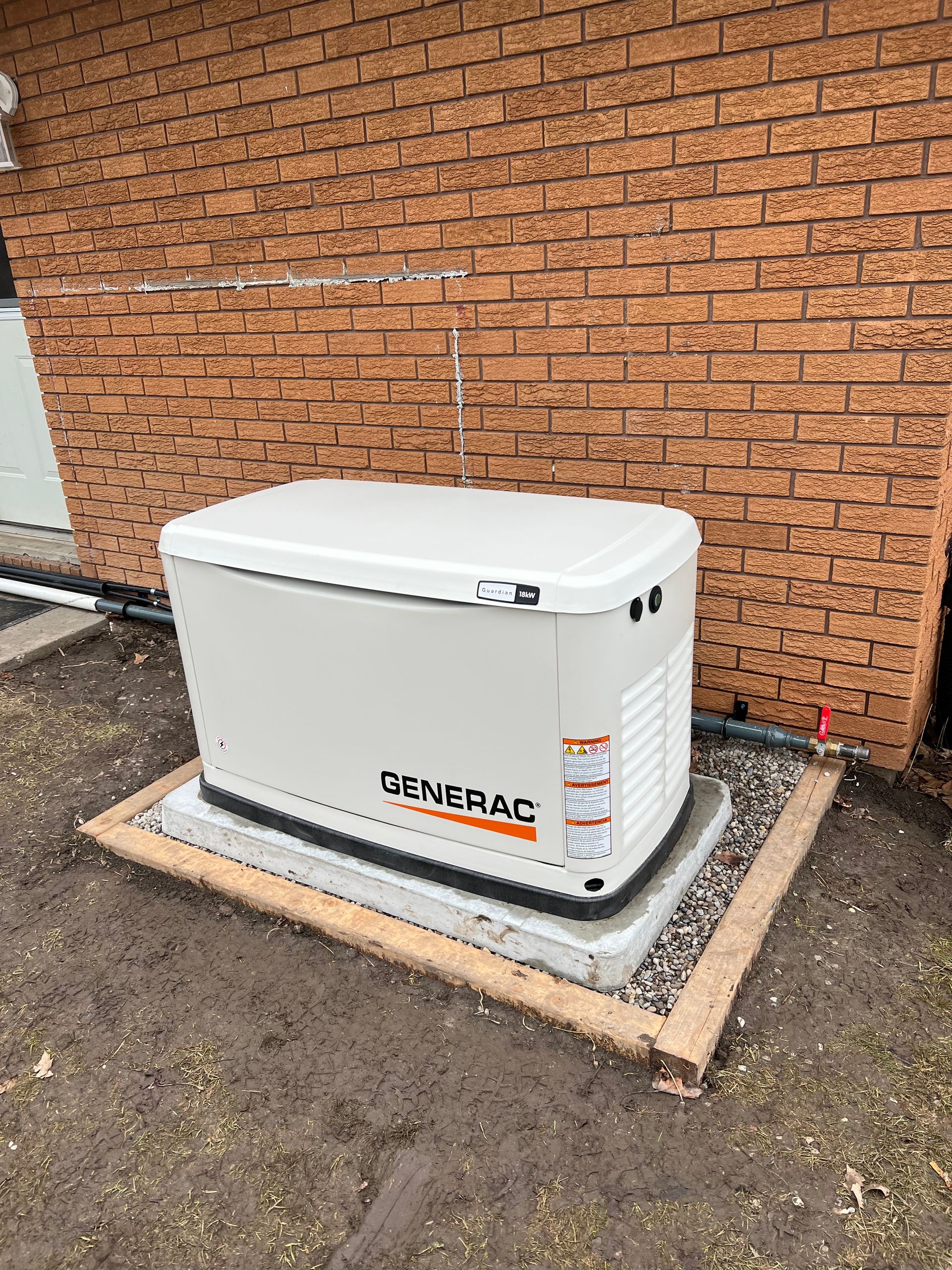 A generator is sitting in front of a brick building.