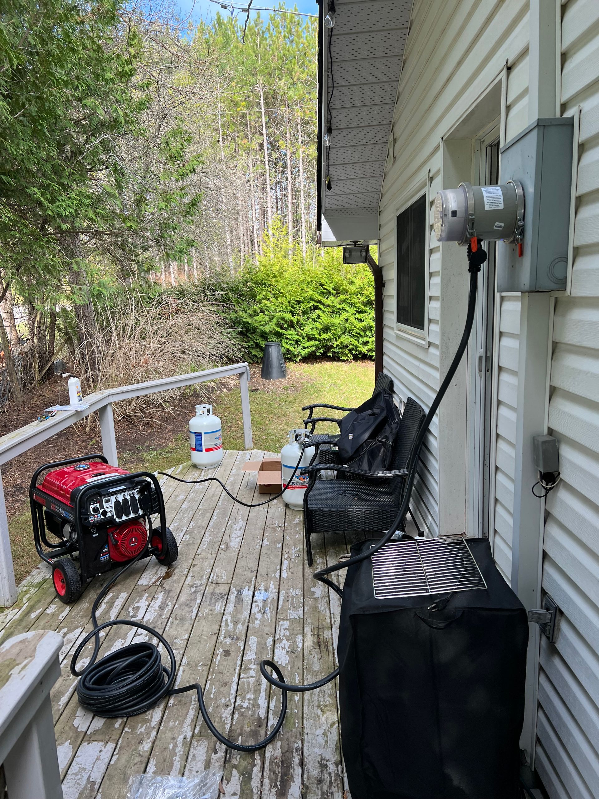 A generator is sitting on a deck next to a house.