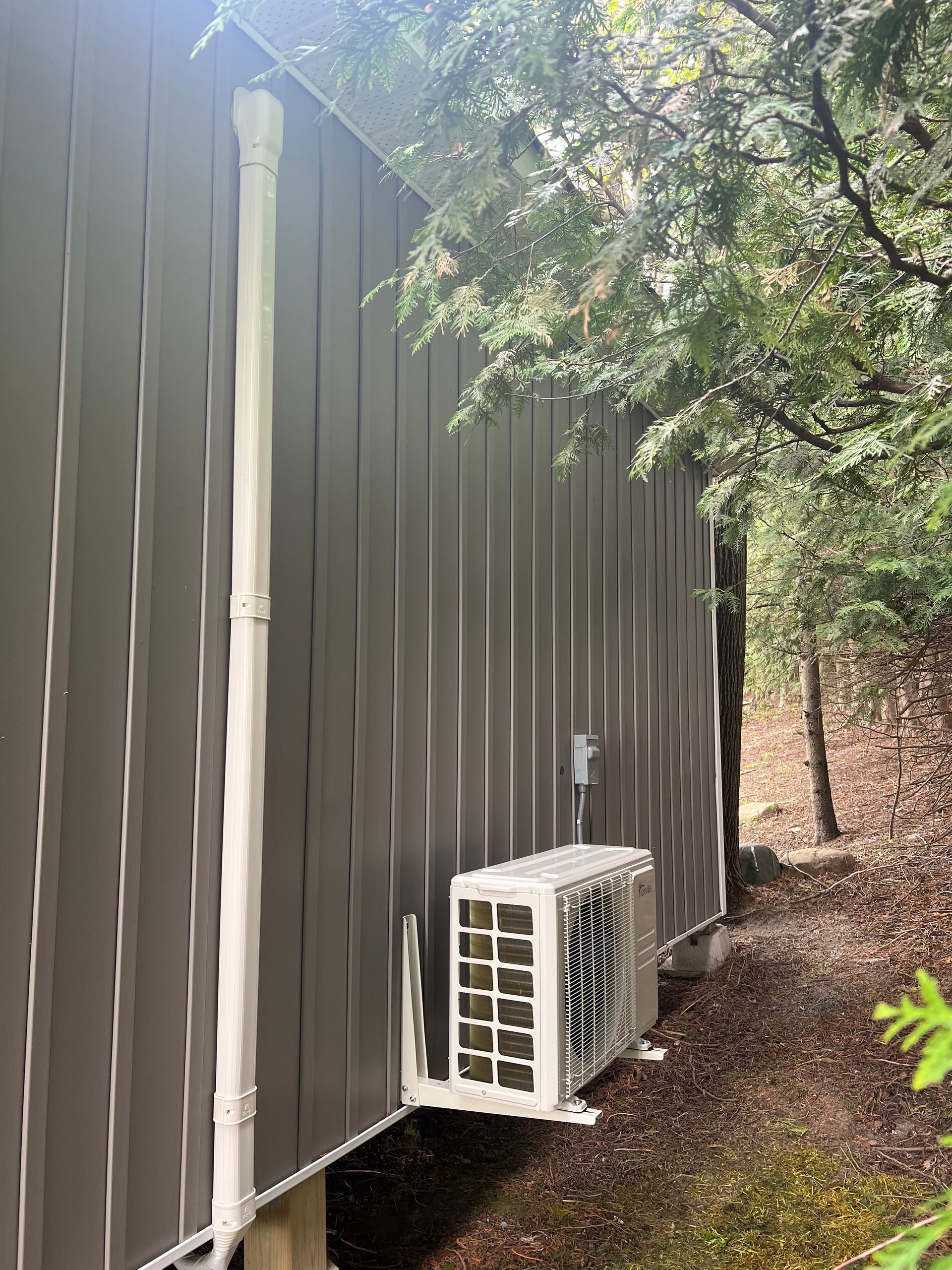 A white air conditioner is mounted on the side of a building.