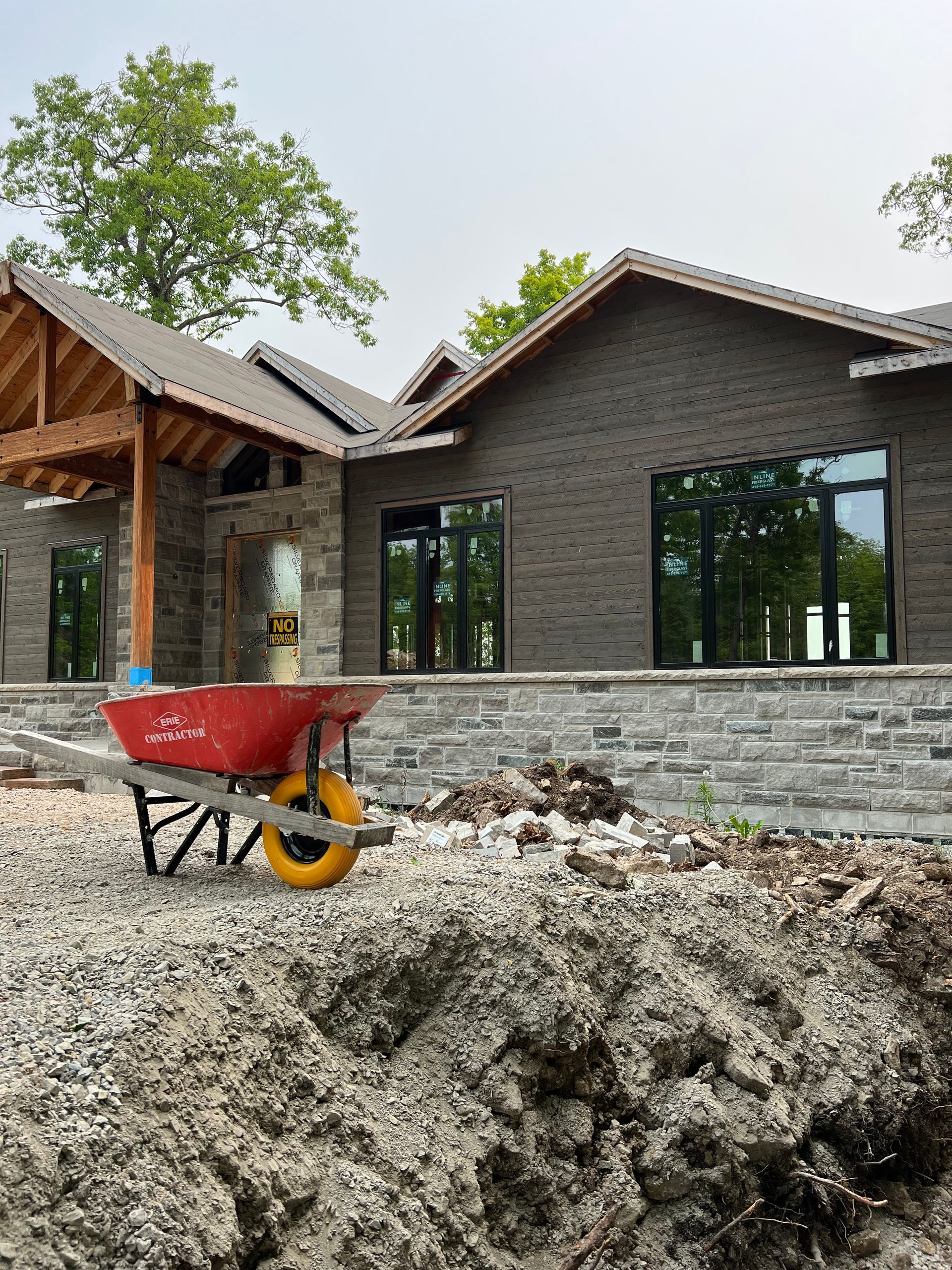 A red wheelbarrow is parked in front of a house under construction.